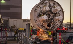 Workers cut the storage rack from the base of the drill head as the Boring Company prepares to lower the drill head for the People Mover tunnel which will connect convention halls as part of the LVCCD Phase 2 construction in the Red Lot east of the south Hall at the Las Vegas Convention center on Monday, Oct. 28, 2019. (Mark Damon/Las Vegas News Bureau)