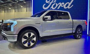 ford f-150 lightning in front of ford logo